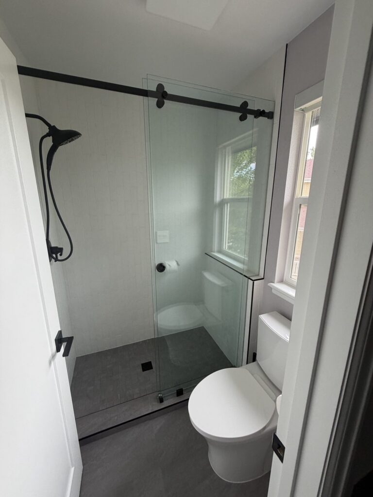 Bathroom remodel with black sliding glass shower door by Brimie Contractors