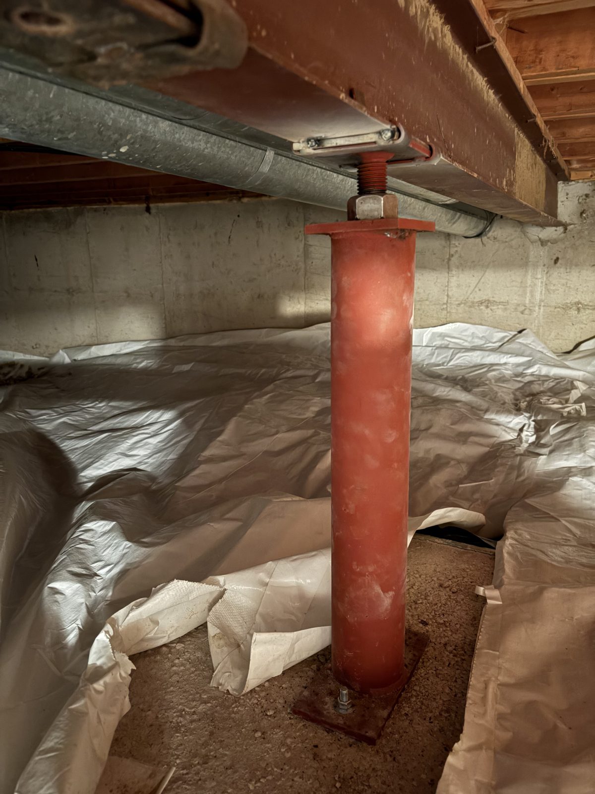 After: red steel support post bolted to its base plate with the vapor barrier restored, Centennial