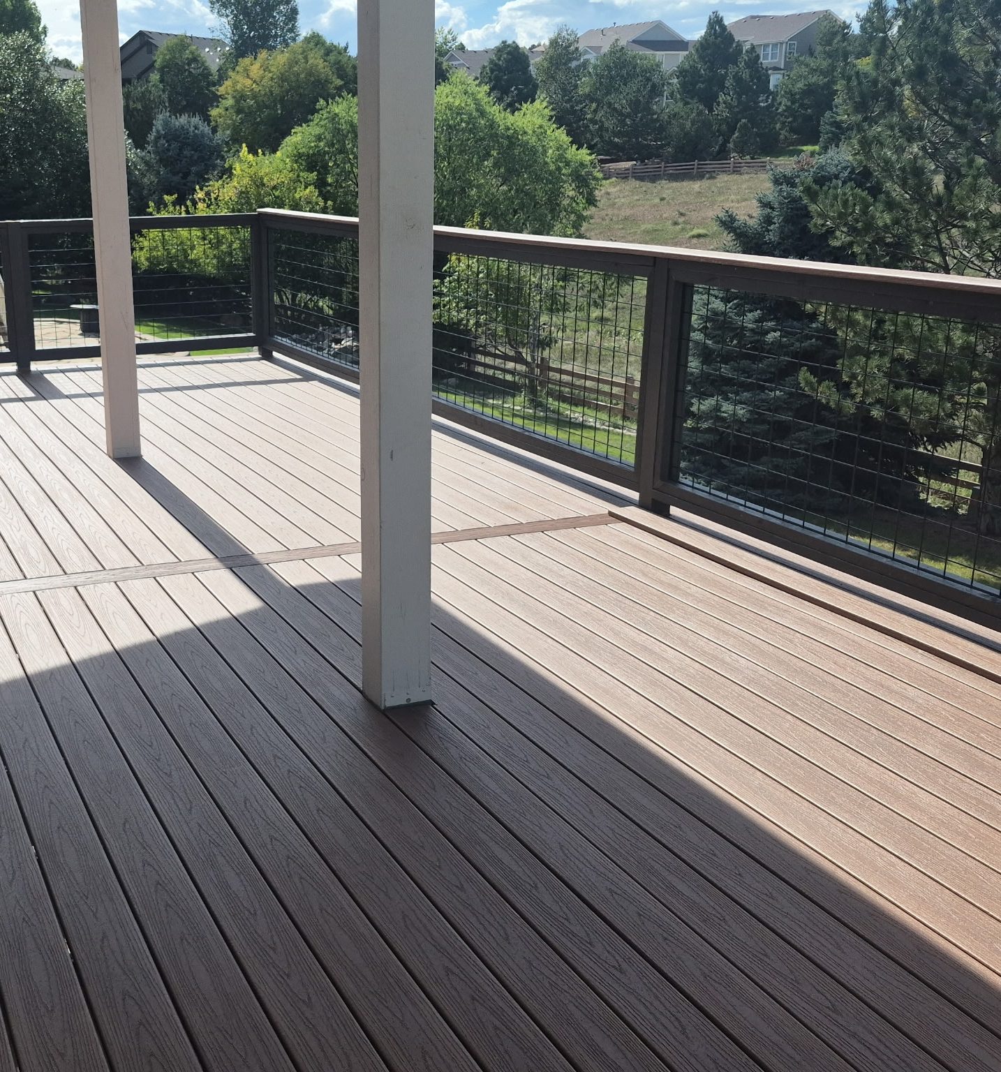 Covered composite deck with black hog-wire railing overlooking open space