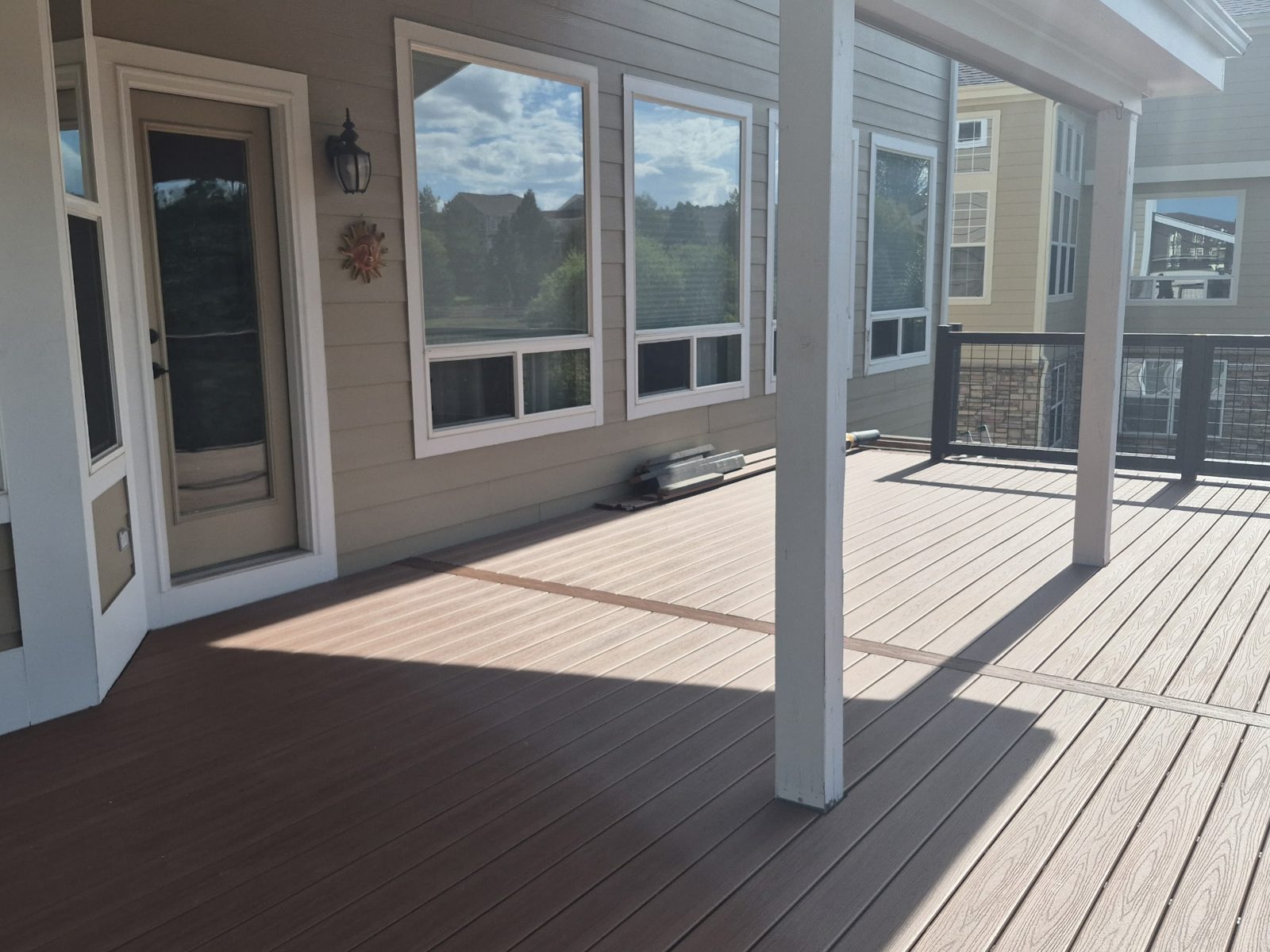 Covered composite deck along the back of the house with white support posts