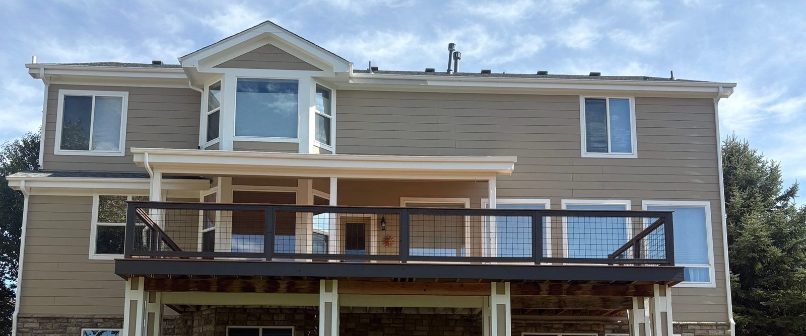 Second-story composite deck with black hog-wire railing across the back of the house by Brimie Contractors