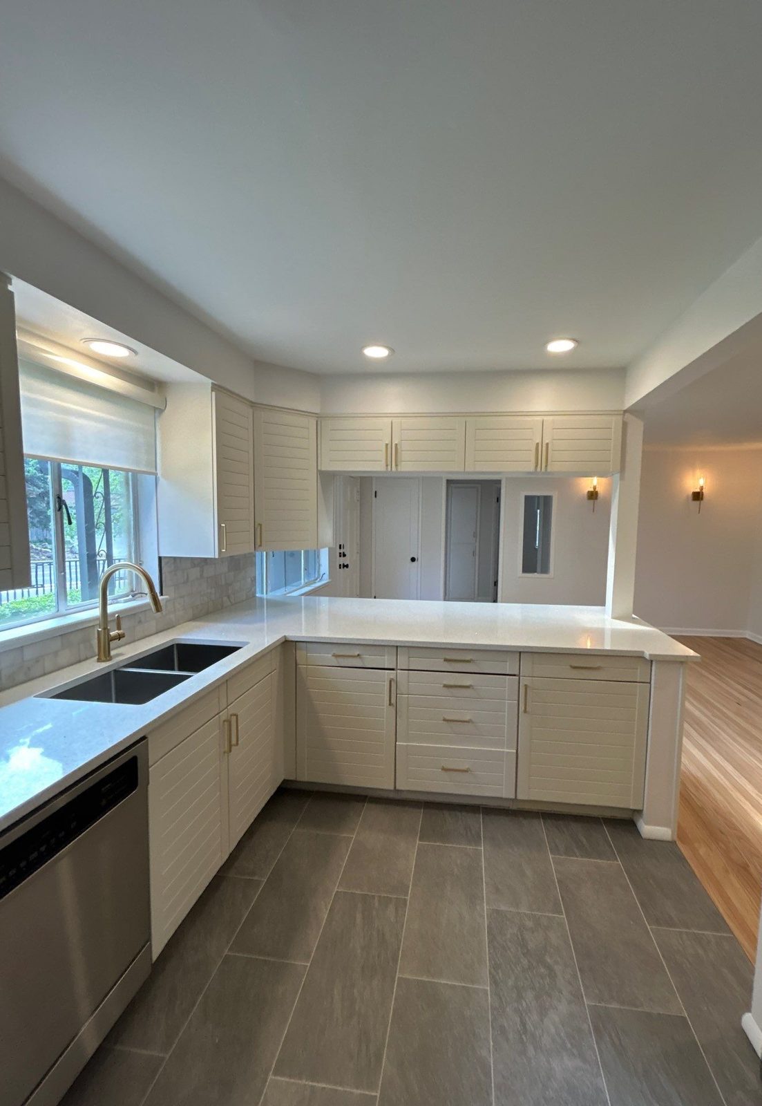 After: white cabinets, quartz peninsula, undermount sink and brass faucet, Denver kitchen remodel