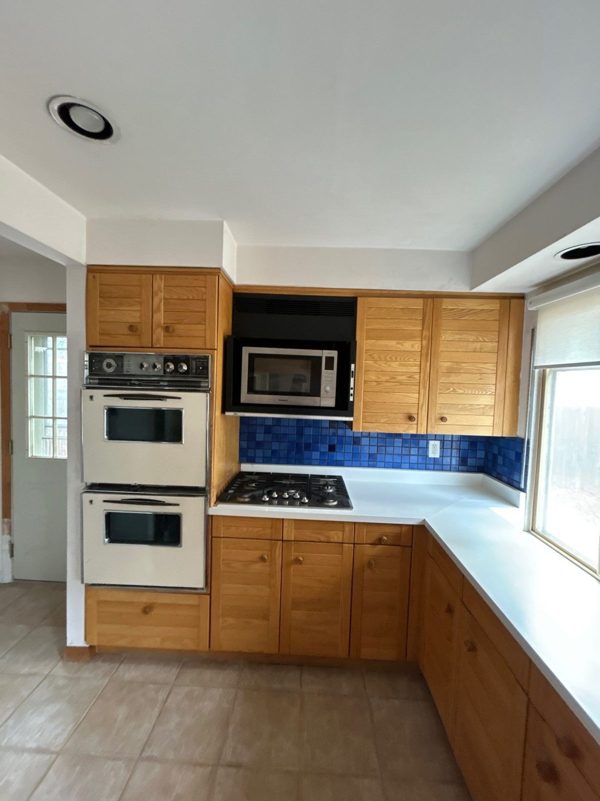 Before: oak louvered cabinets, almond wall ovens and blue tile backsplash, Denver kitchen