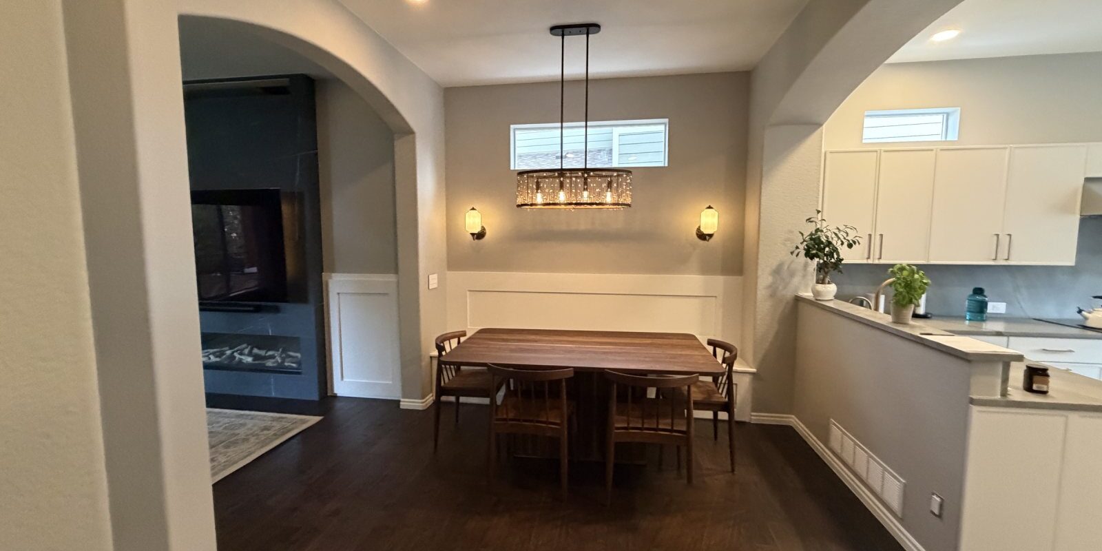 After: Highlands Ranch dining room with wainscot banquette wall, pendant light and sconces, open to the kitchen and the new fireplace wall