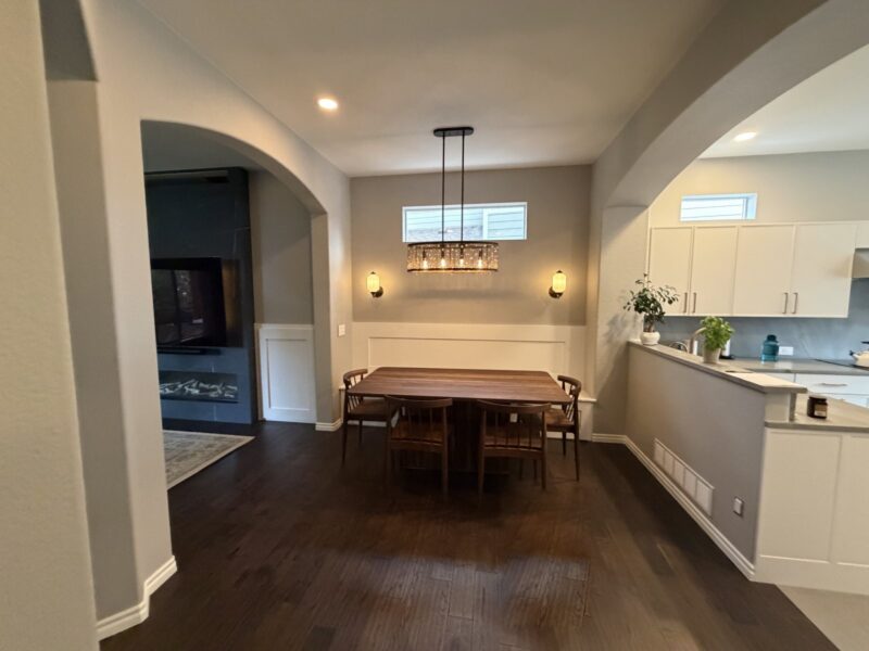 After: Highlands Ranch dining room with wainscot banquette wall, pendant light and sconces, open to the kitchen and the new fireplace wall