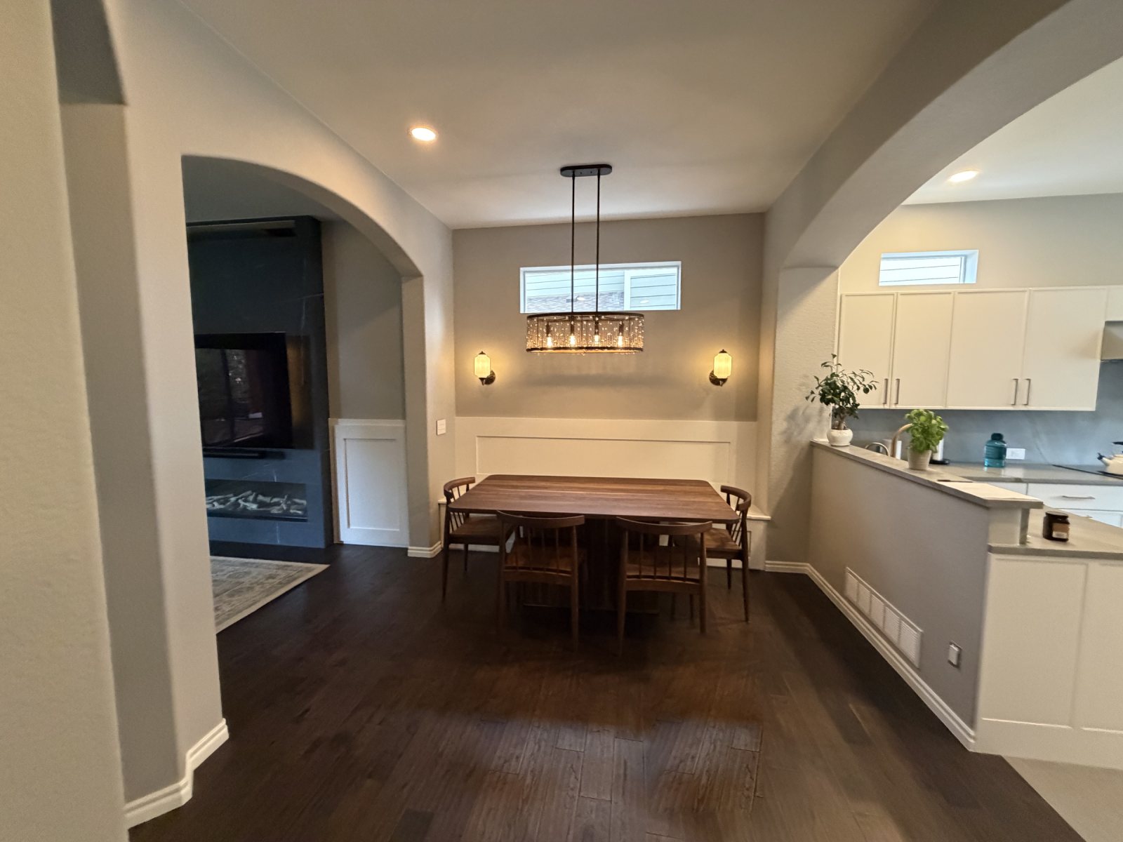 After: Highlands Ranch dining room with wainscot banquette wall, pendant light and sconces, open to the kitchen and the new fireplace wall