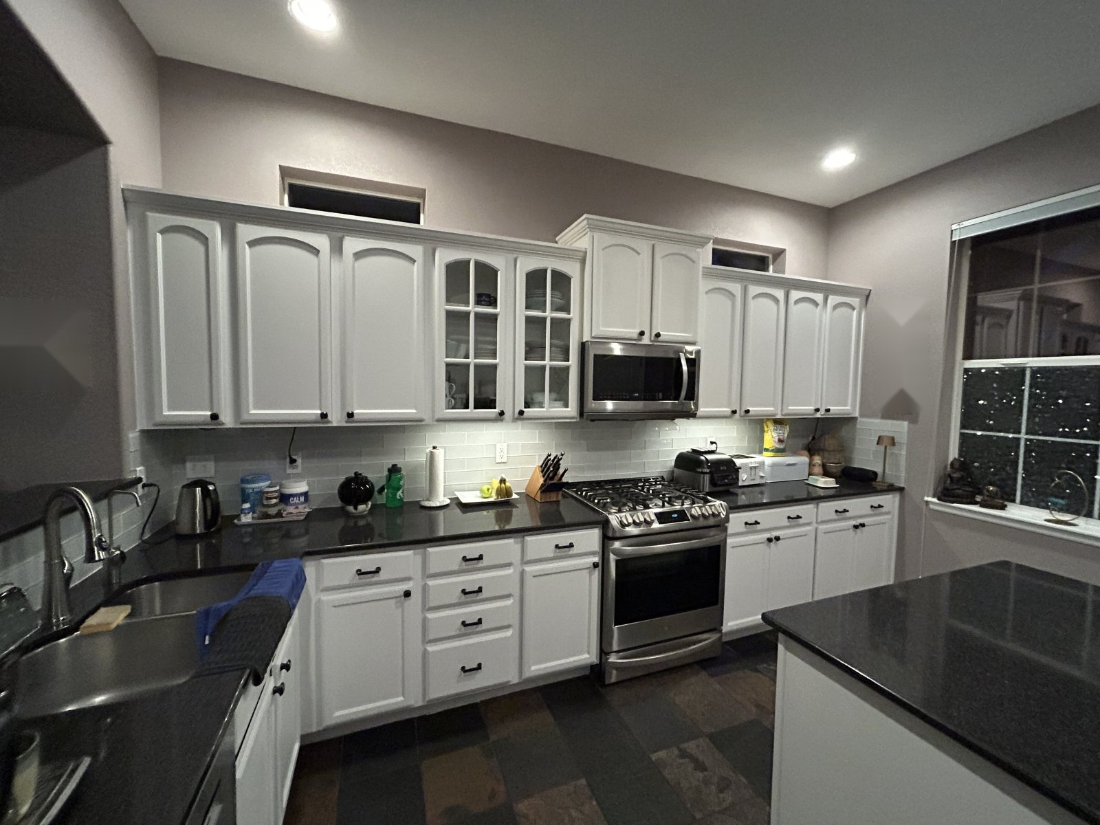 Before: Highlands Ranch kitchen with arched white cabinets, black granite counters and slate tile floor