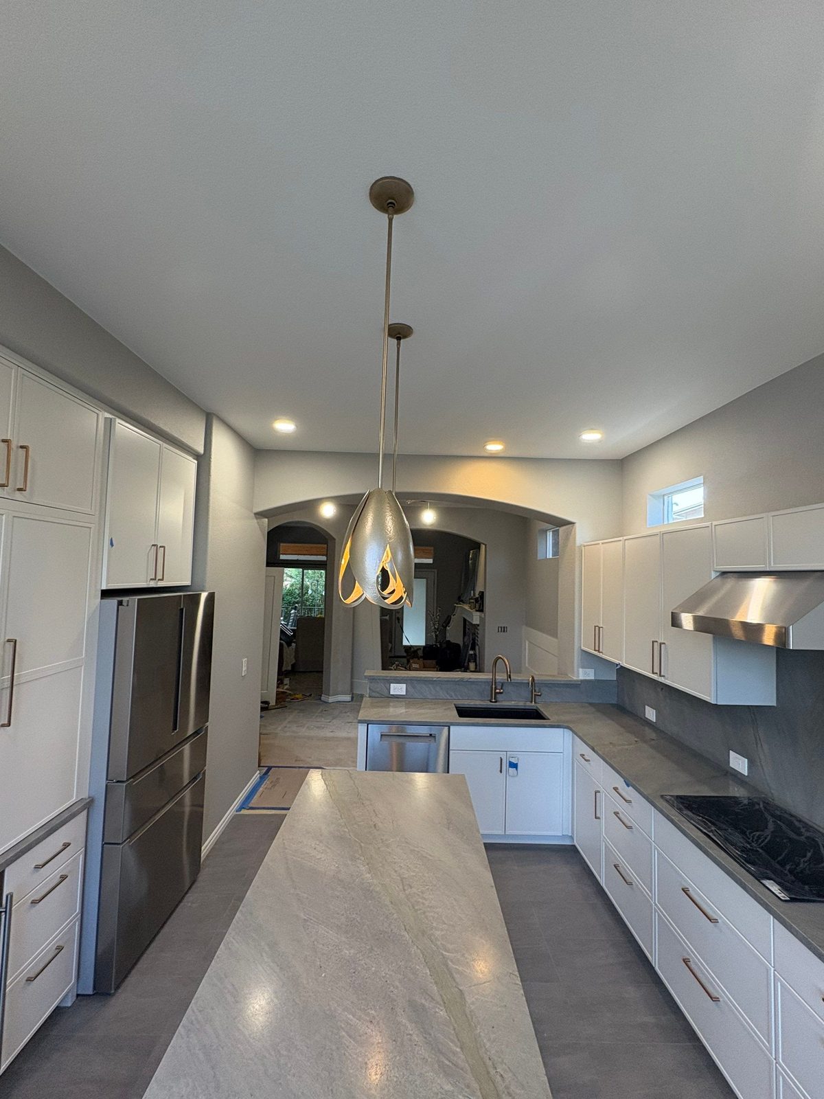 After: Highlands Ranch kitchen remodel with white cabinets, leathered quartz counters, pendant lights and a slab backsplash