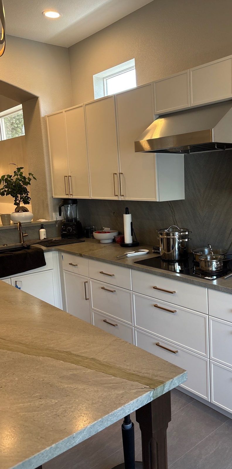 After: stone slab backsplash, stainless hood and brass pulls, Highlands Ranch kitchen remodel