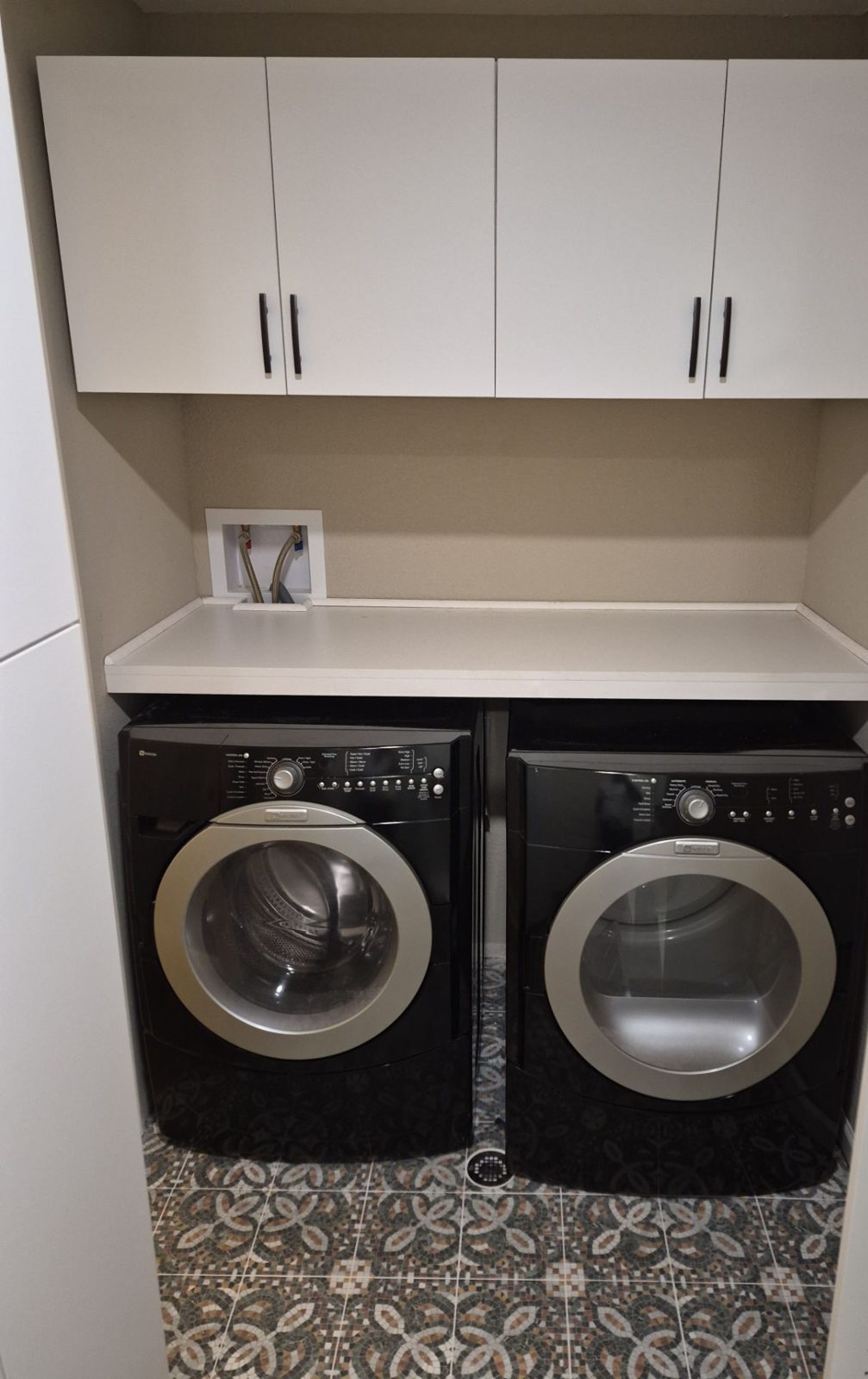 After: laundry with white upper cabinets, counter over the machines and mosaic-pattern tile floor, Highlands Ranch