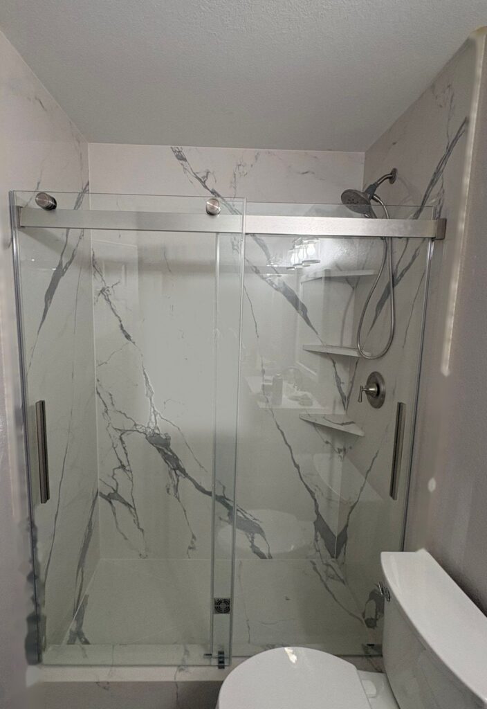 Finished tub-to-shower conversion in Highlands Ranch with marble-look porcelain slab walls and a sliding glass door