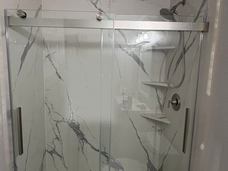 Finished tub-to-shower conversion in Highlands Ranch with marble-look porcelain slab walls and a sliding glass door