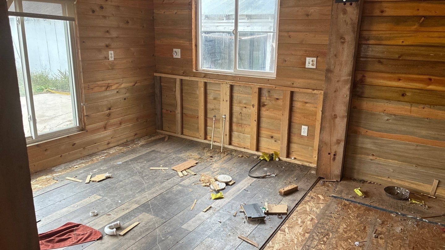 Investor rehab before: gutted room with exposed plank walls and debris, Fort Morgan