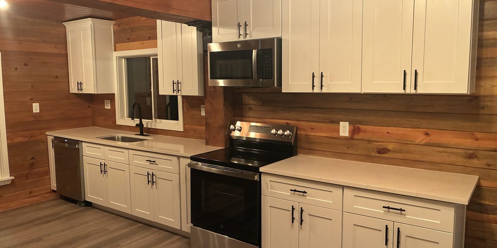 After: Fort Morgan investor rehab kitchen with white shaker cabinets, quartz counters, new appliances and cedar plank walls