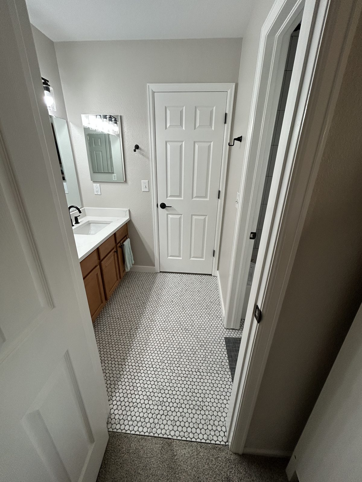 Parker bathroom remodel with double vanity, quartz top, matte black faucets and penny tile floor