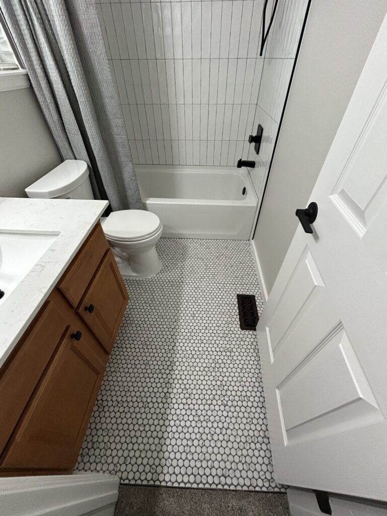After: Parker hall bath with marble-look penny tile floor and quartz vanity top