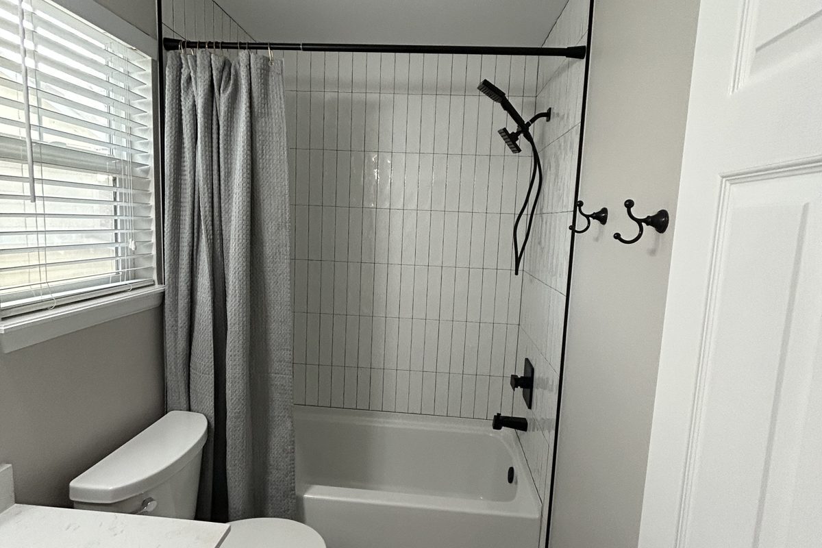 Parker hall bath remodel with white vertical tile, penny tile floor and matte black fixtures