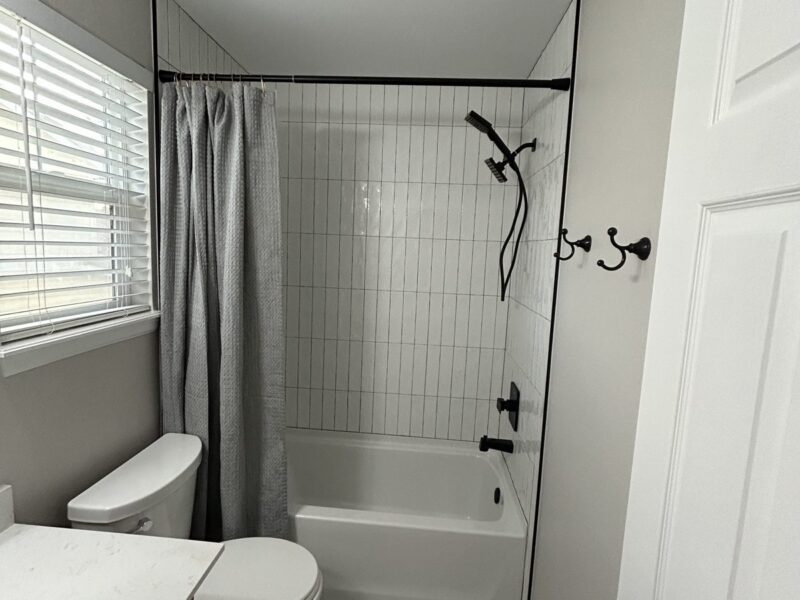 Parker hall bath remodel with white vertical tile, penny tile floor and matte black fixtures