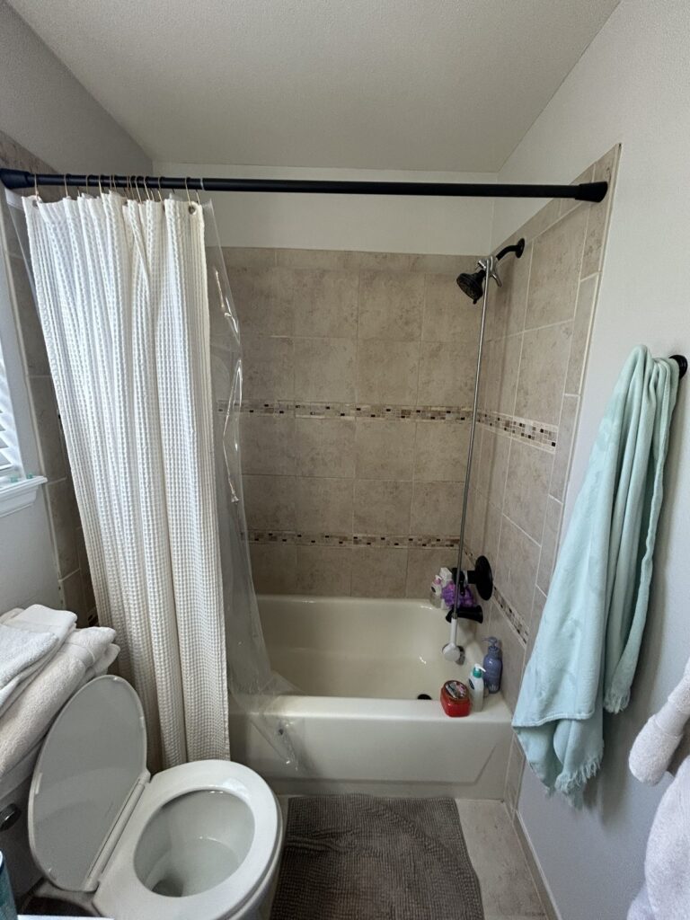 Before: Parker hall bathroom with beige tile tub surround and mosaic border