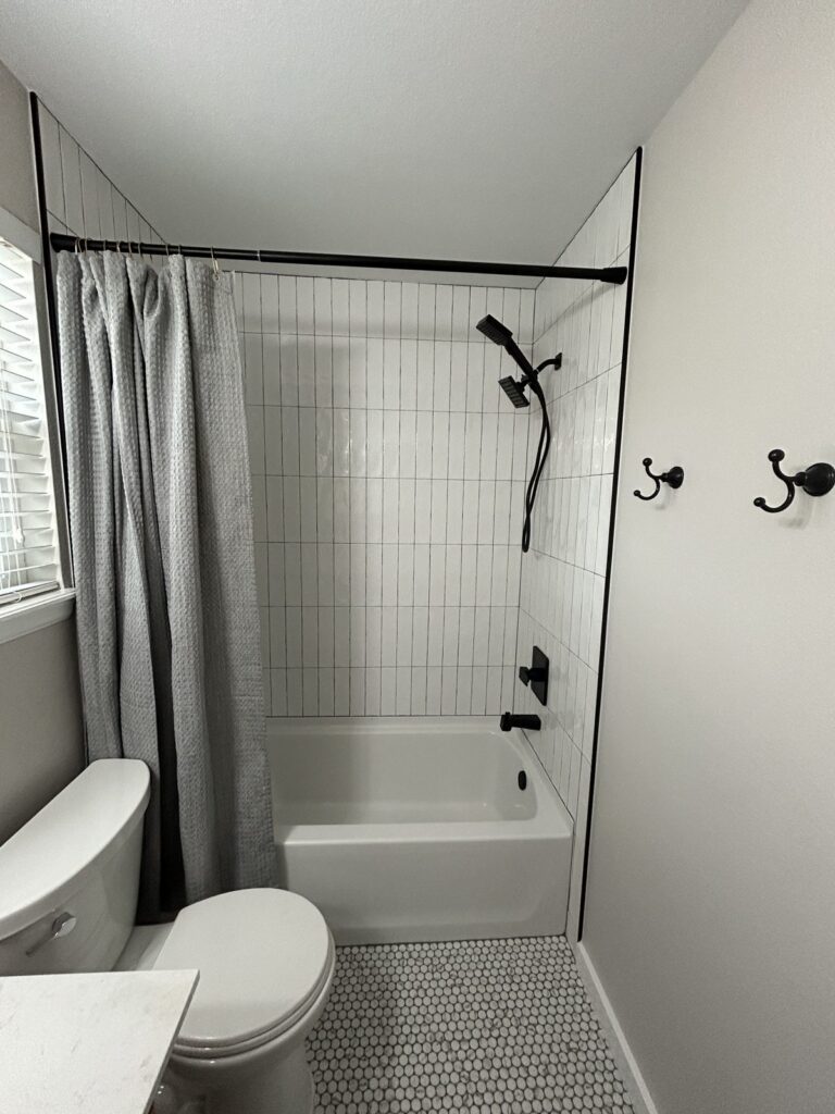 After: Parker hall bath with white vertical stacked tile tub surround and matte black shower system