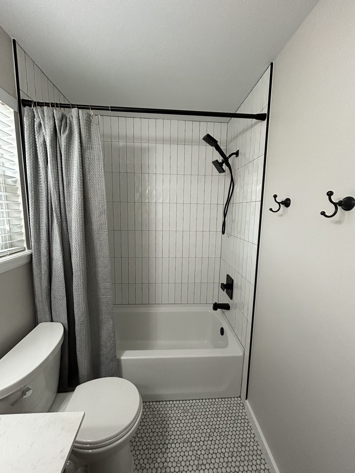 After: Parker hall bath with white vertical stacked tile tub surround and matte black shower system