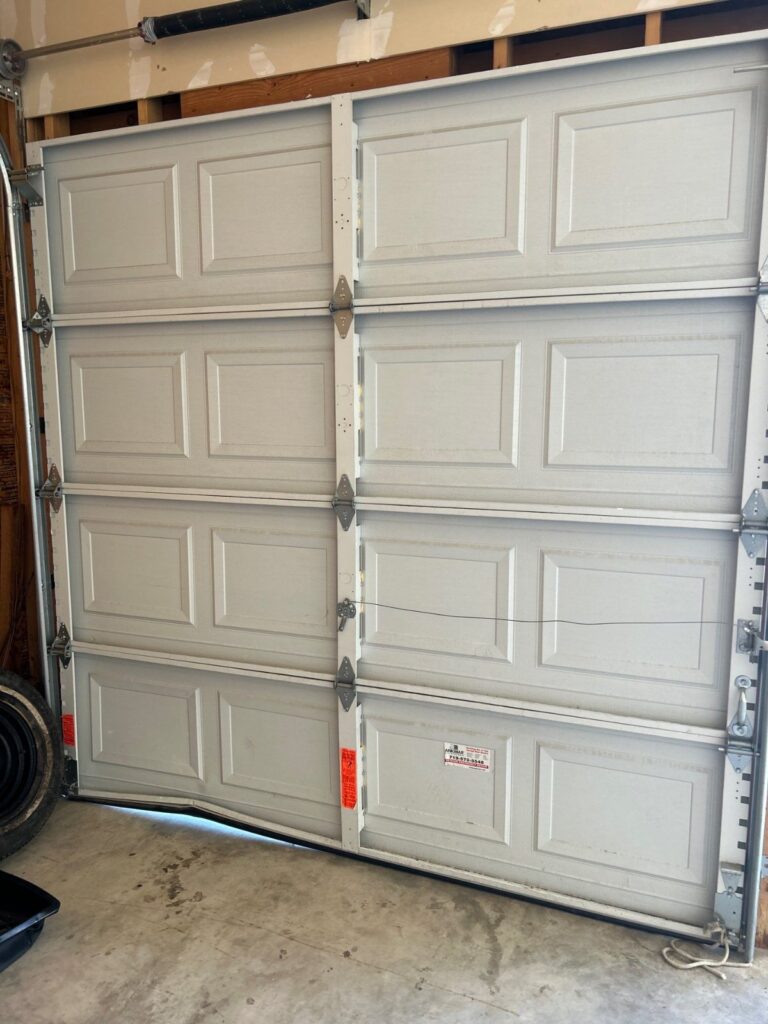 Before: damaged panel on the third-car garage door