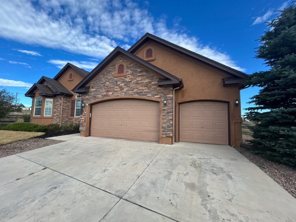 After: garage doors and exterior trim painted, damaged door panel replaced