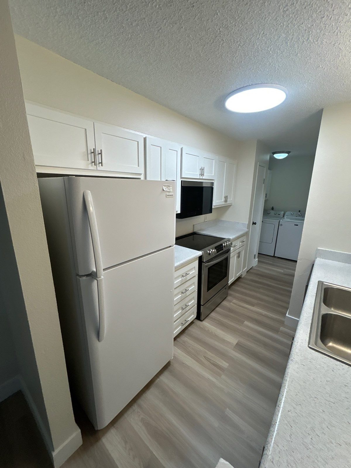 After presale repair, Denver kitchen: white shaker cabinets, light counters and LVP